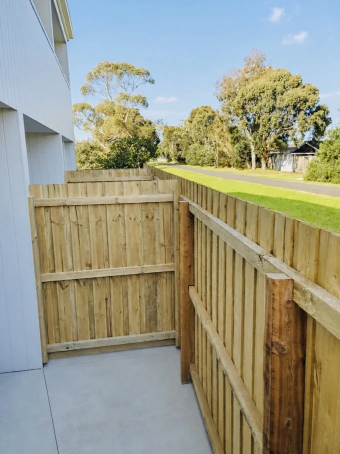 Timber side fence and gate beside a white home